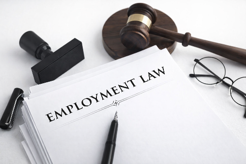 Employment law documents on a desk with a judge’s gavel, pen, and eyeglasses. Gangi Law offers employment law assistance to employers and employees.